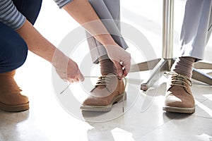 Adult Daughter Helping Senior Man Tie Shoelaces photo