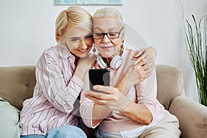 Adult Daughter Helping Senior Woman with Mobile Phone