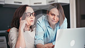 Adult daughter and her mature mother making online shopping