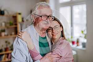 Adult daughter hugging her senior father when visitng him at home.