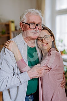 Adult daughter hugging her senior father when visitng him at home.