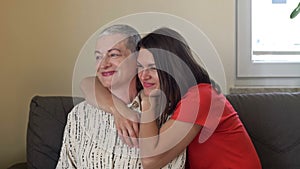 An adult daughter hugs her mother. An older woman has hair regrowth after chemotherapy. Love, care and support in the