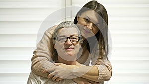 An adult daughter hugs her mother. An older woman has hair regrowth after chemotherapy. Love, care and support in the