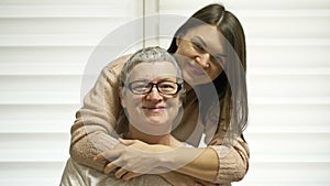 An adult daughter hugs her mother. An older woman has hair regrowth after chemotherapy. Love, care and support in the