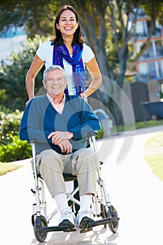 Adult Daughter Pushing Senior Father In Wheelchair