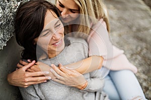 Adult daughter spending time with her mother outdoors. Beautiful daughter holding each other lovingly, hugging photo