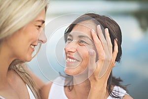 Adult daughter spending time with her mother outdoors. Beautiful daughter holding mother's face lovingly photo