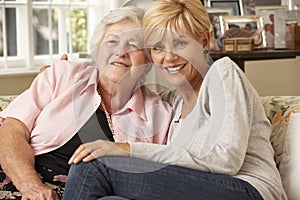 Adult Daughter Visiting Senior Mother Sitting On Sofa At Home