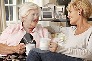 Adult Daughter Visiting Senior Mother Sitting On Sofa At Home