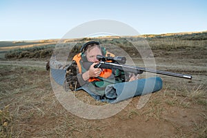 Adult deer hunter aiming long-range rifle