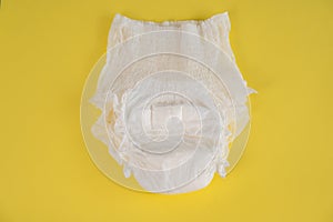 Adult diaper on a yellow background. Incontinence problems.