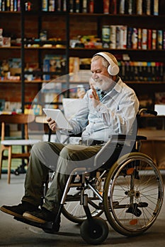 Adult disabled man in wheelchair listen to music