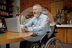 Adult disabled man in wheelchair using laptop