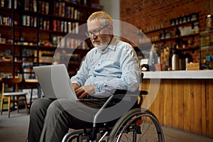 Adult disabled man in wheelchair using laptop