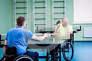 Adult disabled men in a wheelchair playing table tennis