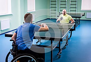 Adult disabled men in a wheelchair playing table tennis