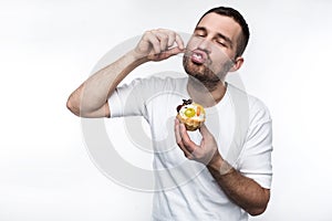 Adult is divouring sweet creamy dessert. He is enjoying the process of eating it. Isolated on white background.