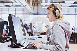 Adult education, student in headphones working on computer in the library