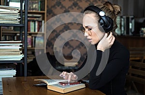 Adult education, student in headphones working in the library or classroom of university