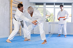 Adult and elderly men training judo fight