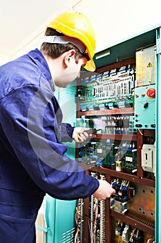 Adult electrician builder engineer worker testing electronics in switch board