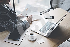 Adult elegant banking finance analyst working at sunny office on laptop while sitting at wooden table.Businessman