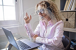 Adult entrepreneaur pretty woman speak on video call conference zoom using laptop computer and headphones with microphone -