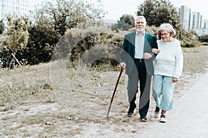 An adult European couple walks around the city. A walk in the fresh air grandparents go by the hand in urban