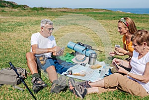 Adult family having a picnic and playing cards during an excursion