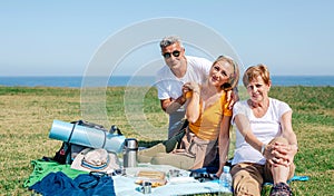 Adult family looking at camera sitting on a blanket having picnic
