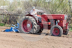 adult farmer working during tractor plowing fields preparing land for sowing. Farm work