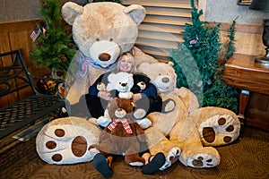 Adult female cuddles with a bunch of giant teddy bears