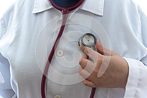 Adult female doctor examine herself with red stethoscope