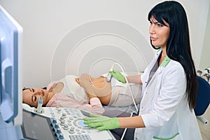 Adult female gynecologist doing ultrasound examination to pregnant woman