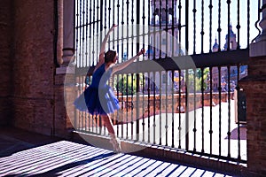 Adult female Hispanic classical ballet dancer in blue tutu making figures on metal gratings against the light