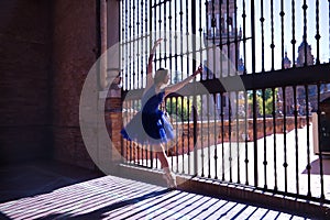 Adult female Hispanic classical ballet dancer in blue tutu making figures on metal gratings against the light