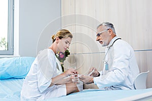 adult female patient with glass of water taking pills from mature male doctor