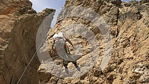 Adult female rock climber descends from a cliff on a rope - rock climbing