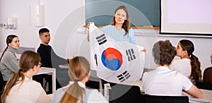 Adult female teacher showing South Korea flag to students