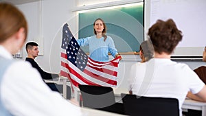 Adult female teacher showing US flag to students