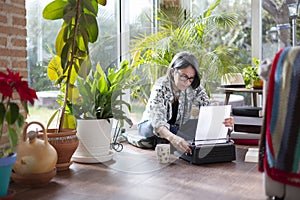 Adult female writer putting a blank sheet of paper on typewriter