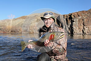Adult fisherman holding steelhead trout