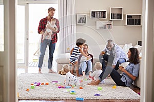 Adult friends with toddlers socialising in sitting room