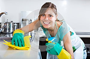 Adult girl dusting surfaces in kitchen