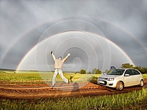 An adult girl in a field with a stormy sky with clouds and grey rainbow. A woman having fun outdoors on rural and rustic