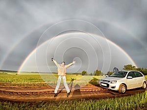 An adult girl in a field with a stormy sky with clouds and grey rainbow. A woman having fun outdoors on rural and rustic