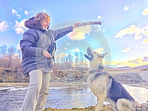 Adult girl with shepherd dog Playing with a stick by the water and taking selfie near water of lake or river. Middle