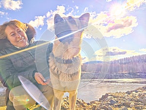 Adult girl with shepherd dog taking selfie near water of lake or river. Middle aged woman and big pet on nature