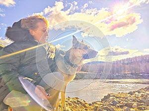 Adult girl with shepherd dog taking selfie near water of lake or river. Middle aged woman and big pet on nature