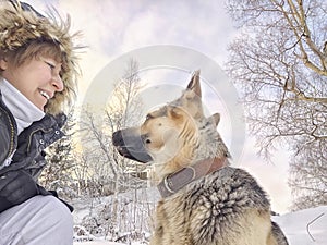 Adult girl with shepherd dog taking selfies in a winter. Middle aged woman and big shepherd dog on nature in cold day